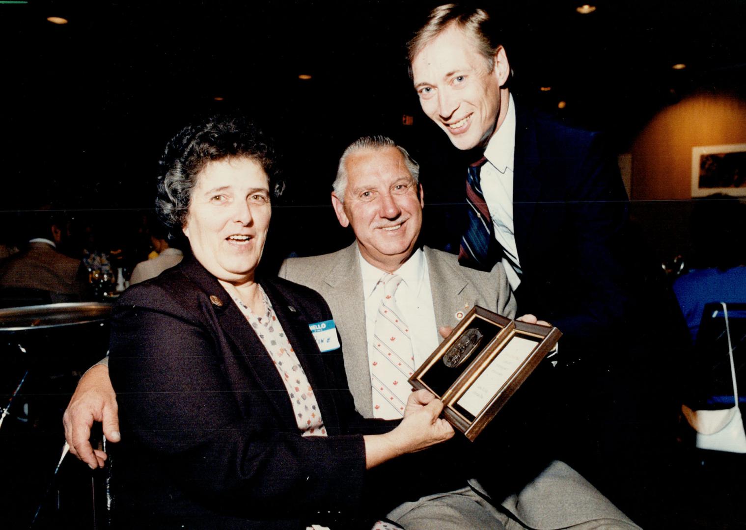 Couple honored: Bill Booker, centre, and wife Rene admire the award presented to them by Mel Finlay, right, executive director of the Metro Children's Aid Society.