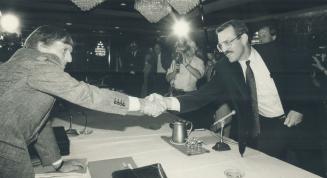 Canadian Auto Workers leader Bob White, left, and Rick Curd of GM, extend a concillatory gesture as contract talks open.