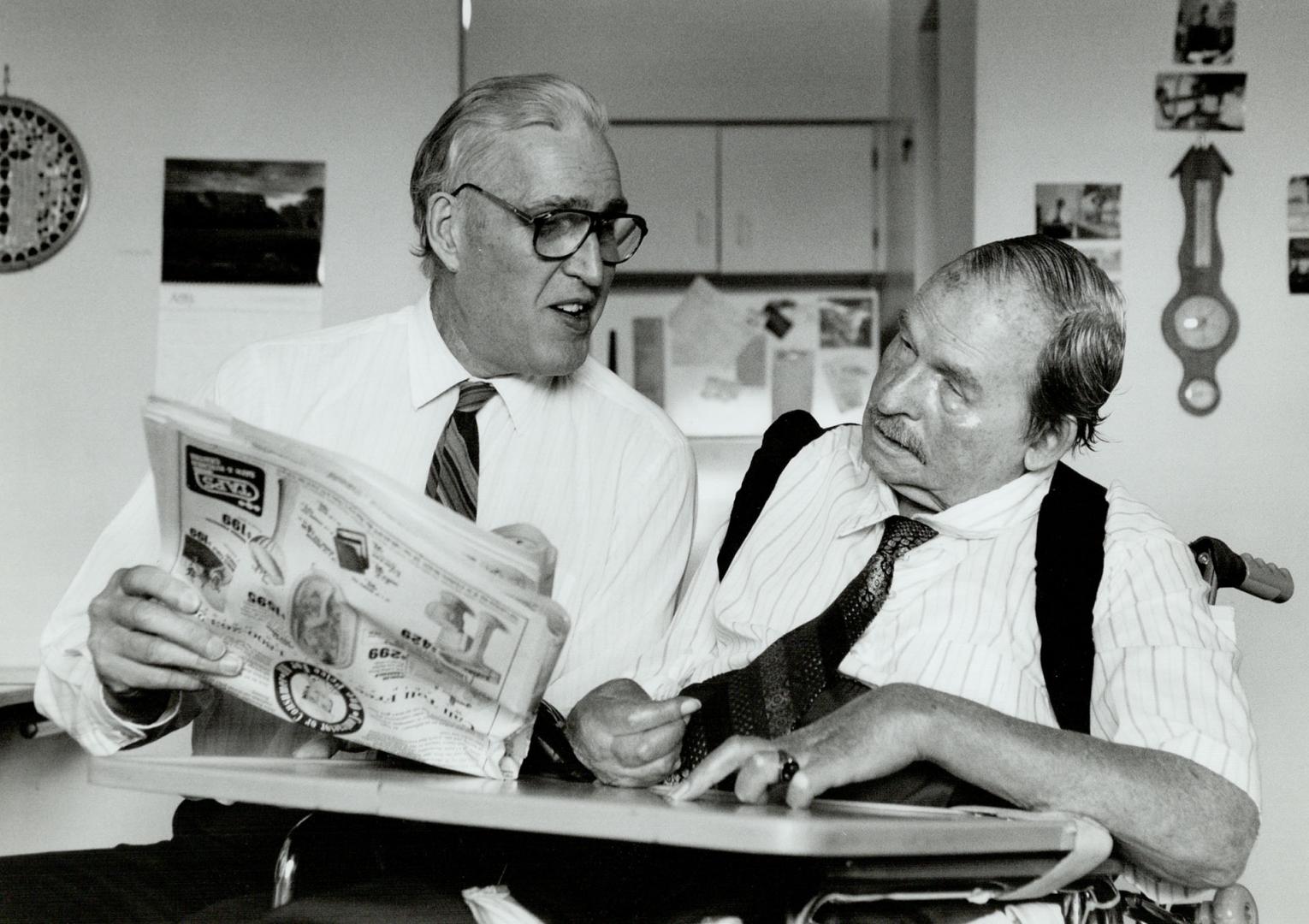 Chris Cook reads the newspaper to roommate Vern Dineen, who has multiple scierosis and is nearly blind.