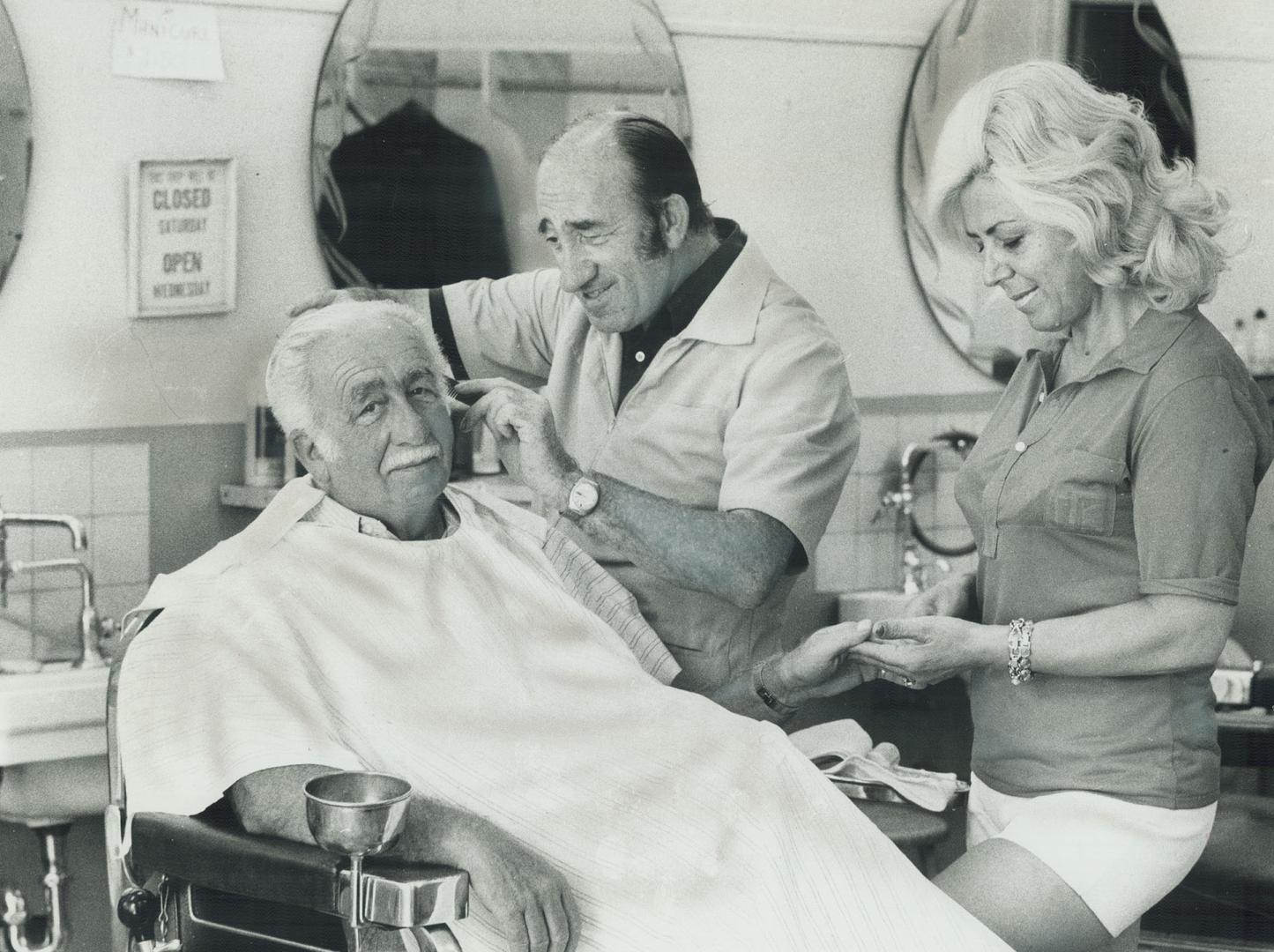 Jack Dancygier gives his attention to customer Lou Sugar in his barber shop at Adelaide and Peter Sts. His manicurist is Gilda Facoetti. A survivor of the concentration camps of Nazi Germany, Jack is grateful for the peace that has come to him and wife in Canada, where they have raised three sons. He and his wife were married secretly by a rabbi in a concentration camp. Their first son was born there, too.