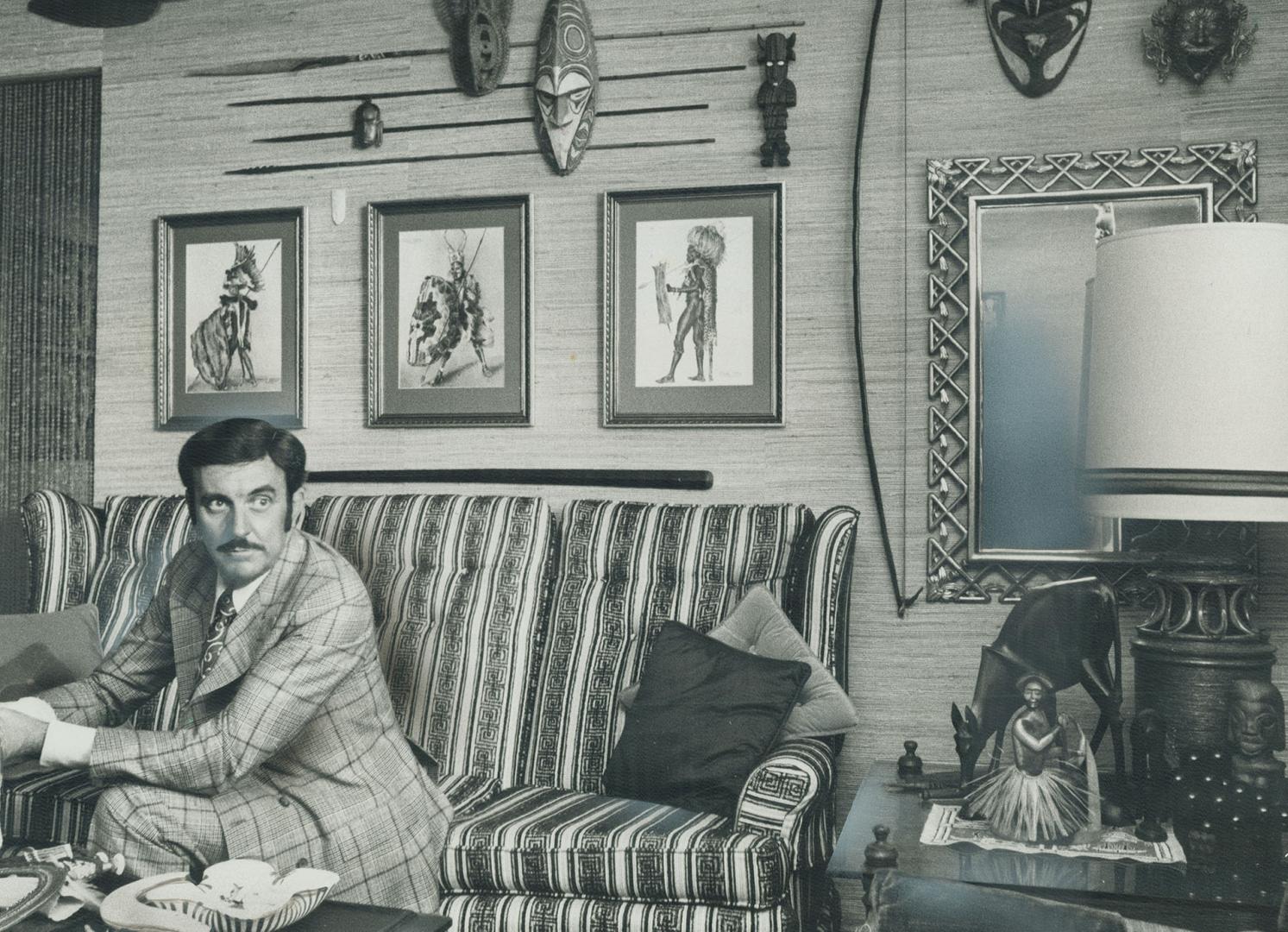 Clive Deverath relaxes in a corner of his living-room devoted to a display of African artifacts. On reprints by Joy Adamson who wrote the book, Born Free. He fingers some Masai warrior beads from Kenya. In his job and on his holidays he travels around collecting handmate crafts. They inspire him, he says. [Incomplete]