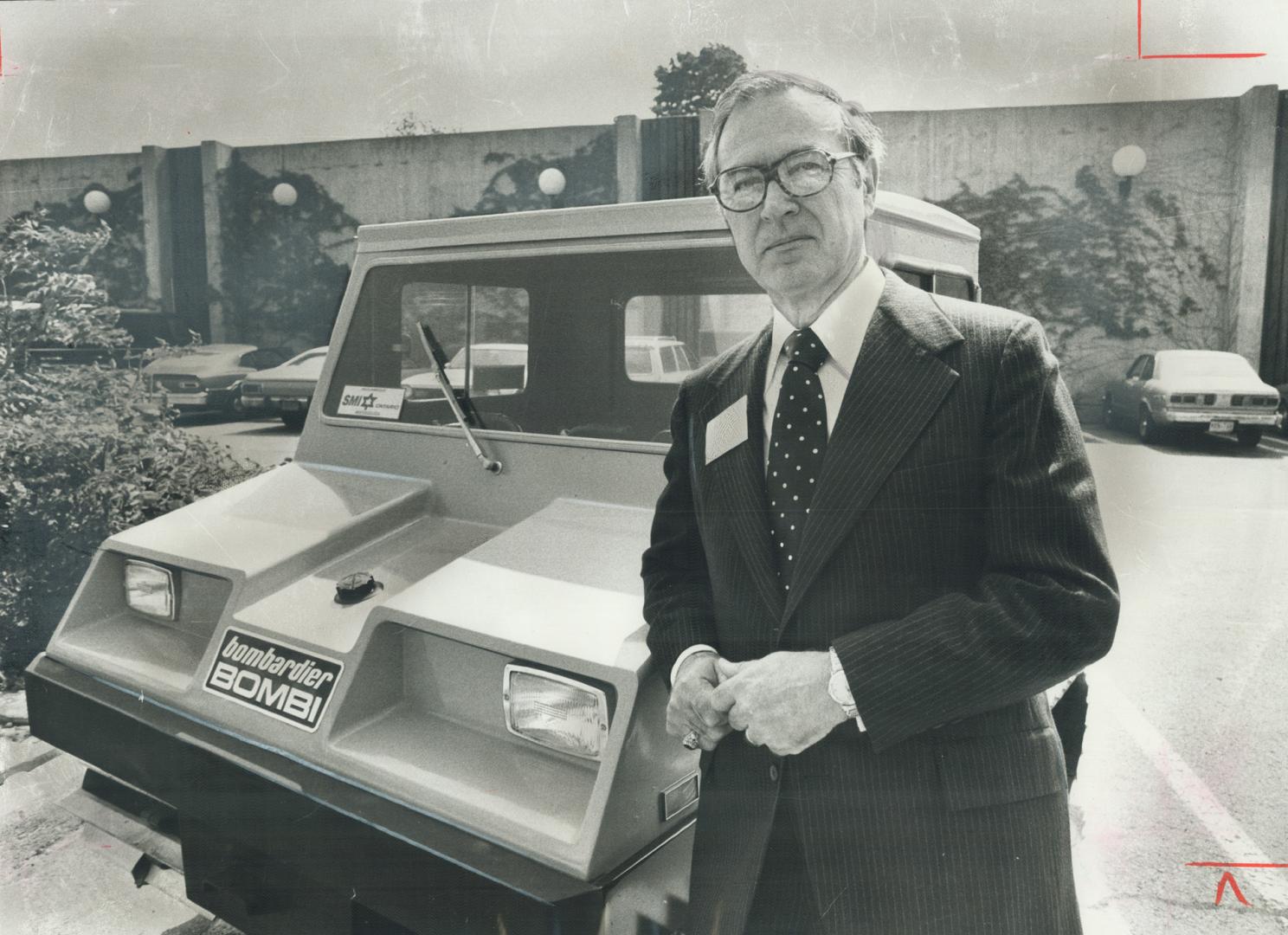 Mortimer Doyle, president of the International Snowmobile Industry Association, poses with large snowmobile outside the Inn of the Park yesterday. Despite temperatures around 26 Celsius, the association is holding its annual congress and discussing such unseasonal topics as Snow Country - Winter Fun for Everyone. Snowmobile sales are expected to reach 250,000 in 1978, figures that should keep manufacturers warm in the long winter nights.