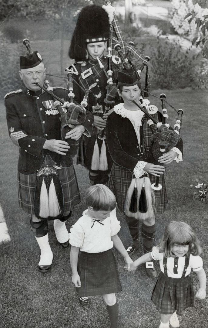 Blowing up a storm in the backyard is this family of pipers, Former Pipe Major Archie Dewar is with son Alex and daughter Frances Lawrie