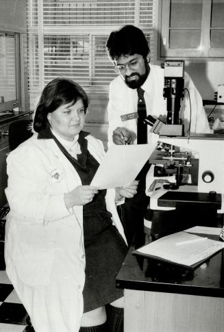 Dr. Ian Dube, director of the first cancer cytogenetics program in Canada, and senior technologist Sandra Johnson, look at lab results from leukemia patients.