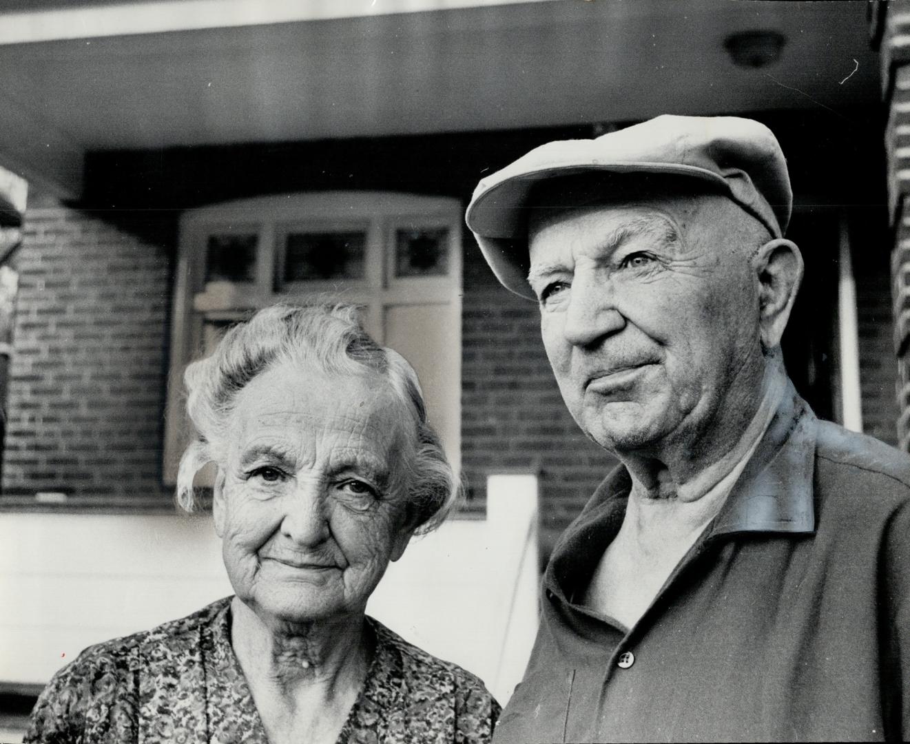 Bilked of their savings of $1,000 by men posing as bank inspectors, 80-year-old Mr. and Mrs. Alex Downie stand outside their home on Kenwood Ave., where they have lived 40 years, as they tell they were swindled. A man took away fifty $20 bills to check s