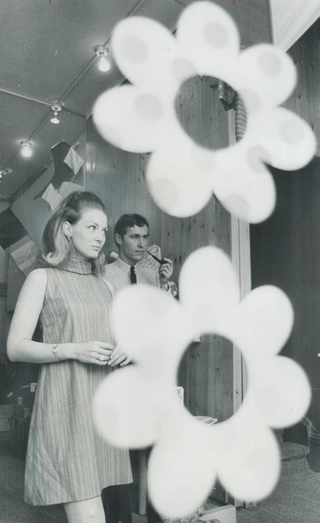 Pretty flower mobiles hang from the ceiling of Phase 1, while Fay and Earl Helland thoughtfully eye store display to see if it suits them.