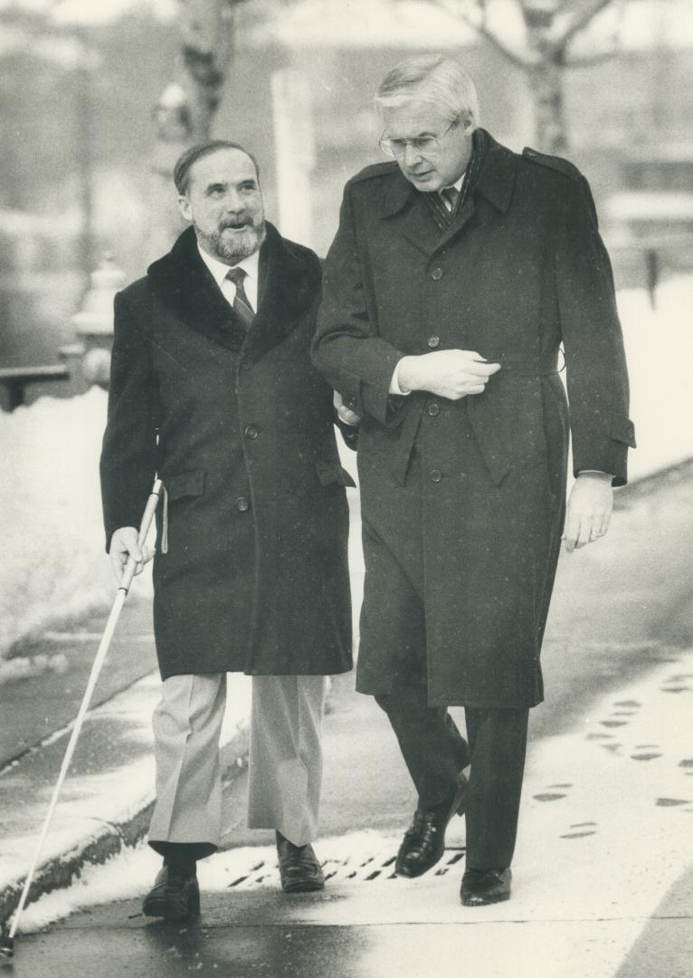 Federal Health Minister Jake Epp helps Dr. Euclid Herie, of the Canadian National Institute for the Blind, cross the street on the way to ceremonies at CNIB headquarters on Bayview Ave. yesterday to kick off White Cane Week. Come See With Me, is the week's theme.