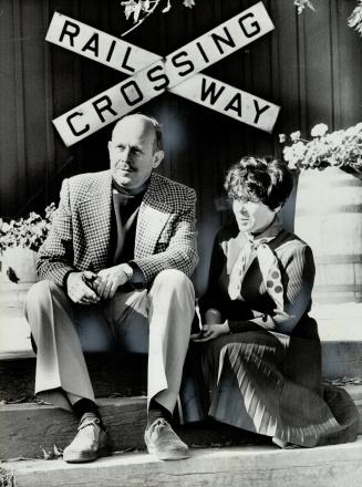 Alex Hacker and Anna Spencer on veranda of general store at Campbellville, Ont. Railway crossing sign was bought for $11 at auction.