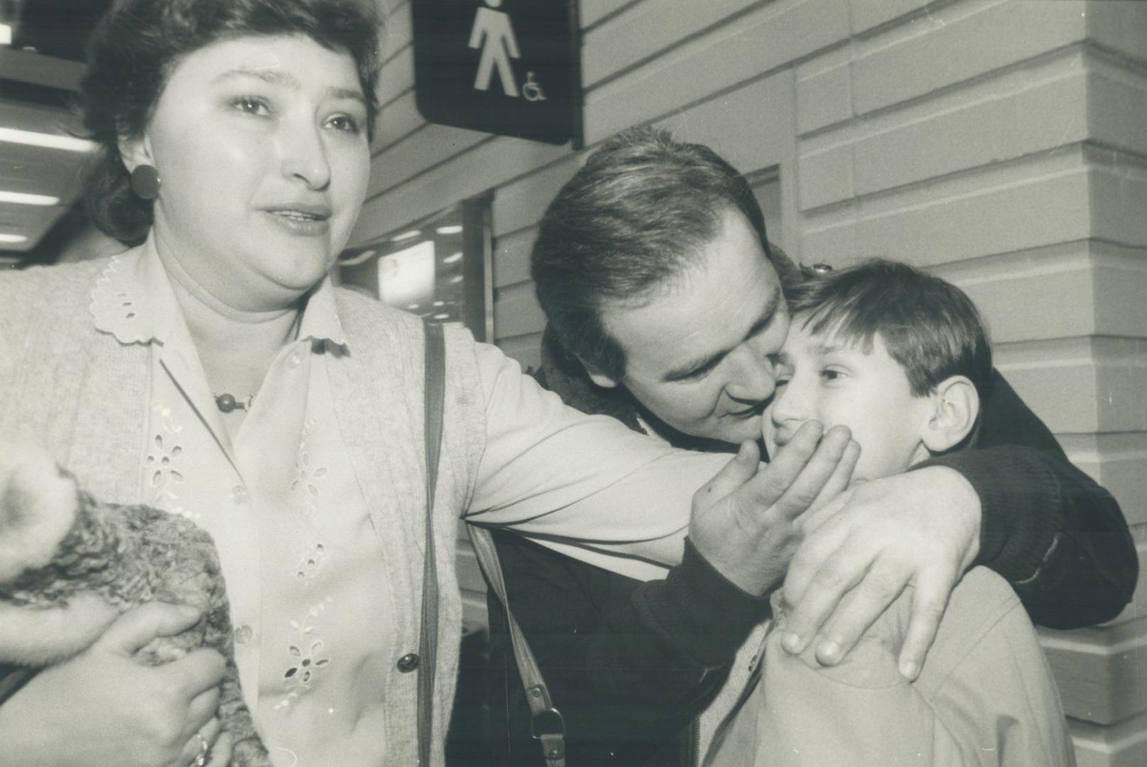 Together again: After a separation of nearly two years, Jerzy and Maria Holbuj-Marcon, embrace their 14-year-old son Wojtek at Pearson international Airport last night after the child and his brother Marek, 12, arrived in Canada from Poland