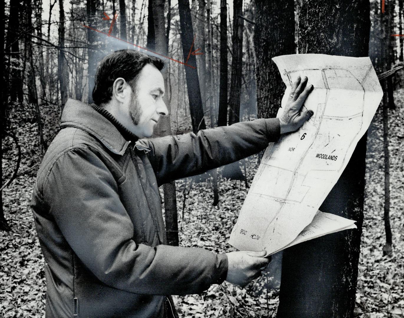 John Ladell, an executive member of Save Our Trees and Streams, scans a map as he and six others walk the proposed realignment of Mississauga Rd