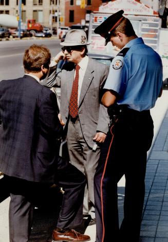 Despondent over loss: Diamon importer Charles Laiman leans against his Cadillac yesterday as he tells police how his briefcase full of gems was stolen when he put it down to pick up a $2 bill