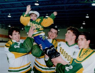 Heartfelt thanks: Trevor Lewis, 6, gets a boost from Wexford Raiders Dave Colquhorn, left, Mike Whitton and Alex Vallee before last night's hockey game