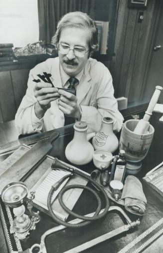 Old medical instruments, including a blood letter that he's holding, are in the collection of Dr. Ramsay Macdonald, a veterinarian.