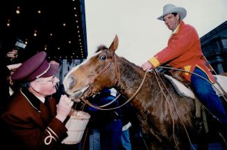 Royal York Hotel doorman Dougall MacDonald is armed and ready - with a bucket of apples and carrots - to hold off Trigger and his rider, Albertan Lloyd Jacobson, yesteray as they fall to hoof it into the hotel lobby