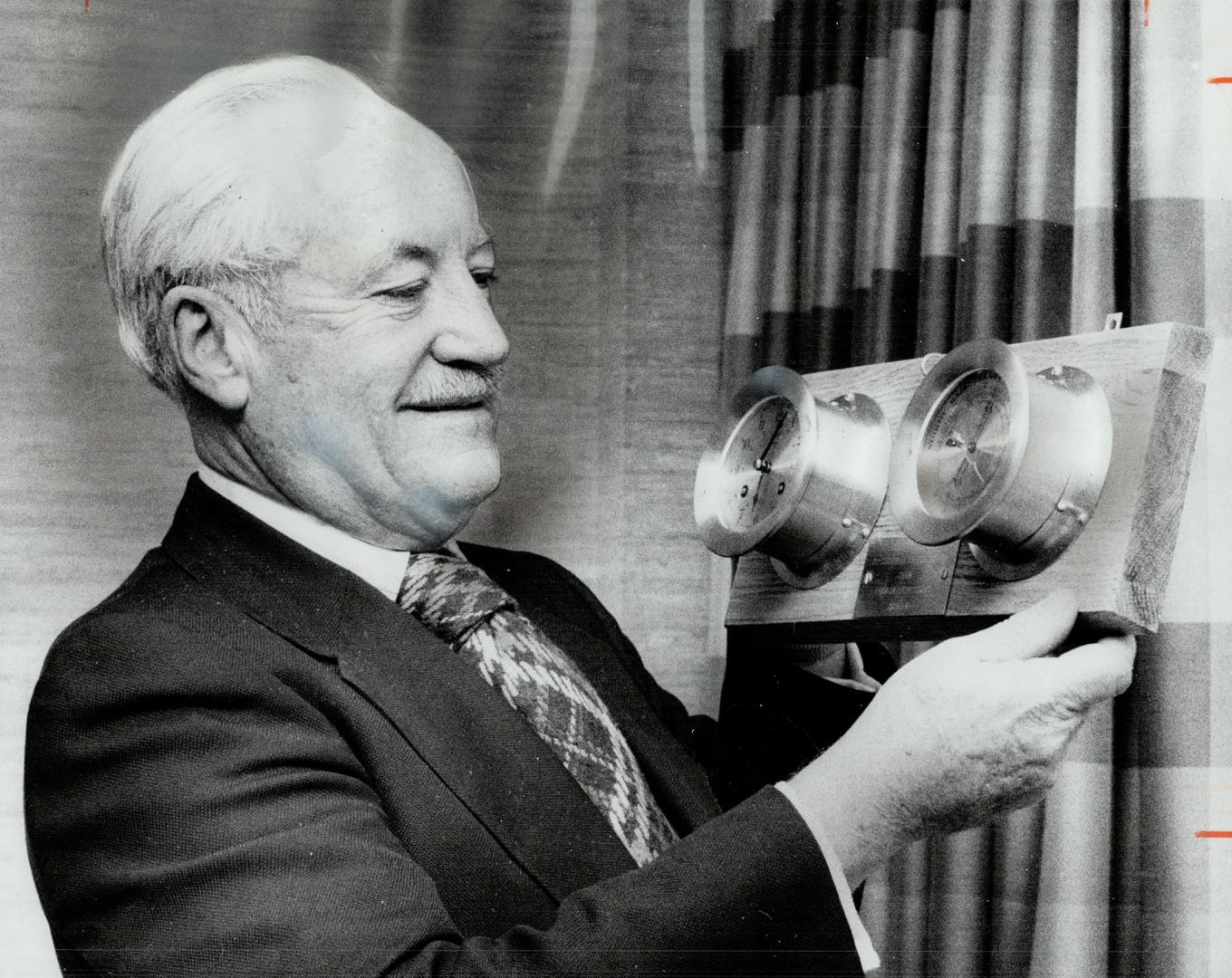 First Chairman of Halton Regional Council, Allan Masson admires brass ship's chronometer and barometer he was given by members of first regional council at their last meeting