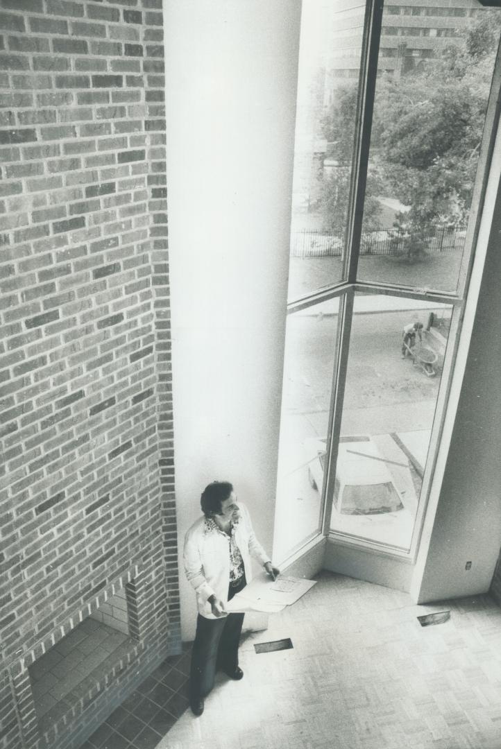 Architect Paul Nightingale, 38, shown above in study of three-bedroom townhouse, solved the problem of 14 ft, wide building lots with use of vertical height, open interiors and three-storey deep bay windows