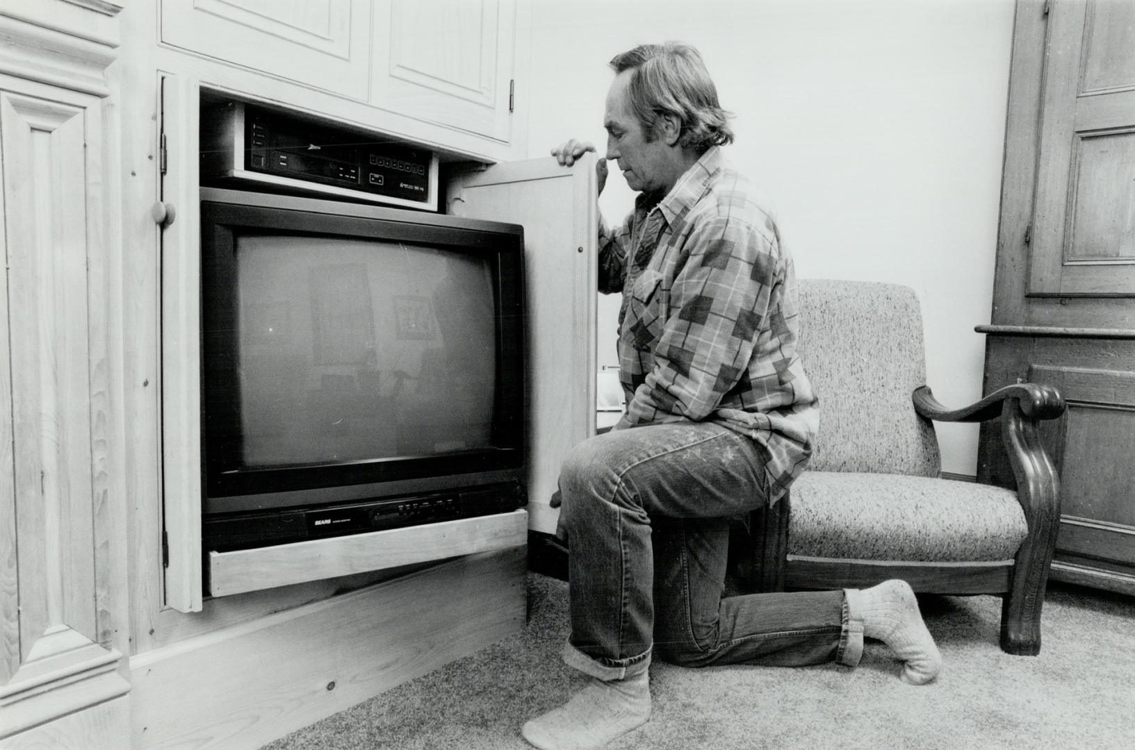 Hiding the modern: Master woodworker Derek Maw demonstrates sliding pine panels that he ingeniously built in the living room to hide the television