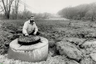 Scarred land: John Minns, 42, checks a manhole leading to a new 2