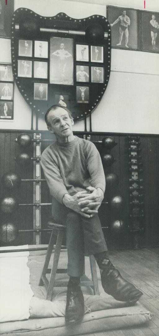 Reminiscing: William (Buster) Oliphant, seated on stool under plaque covered with photographs of father, talks about founding of one-room facility he operates