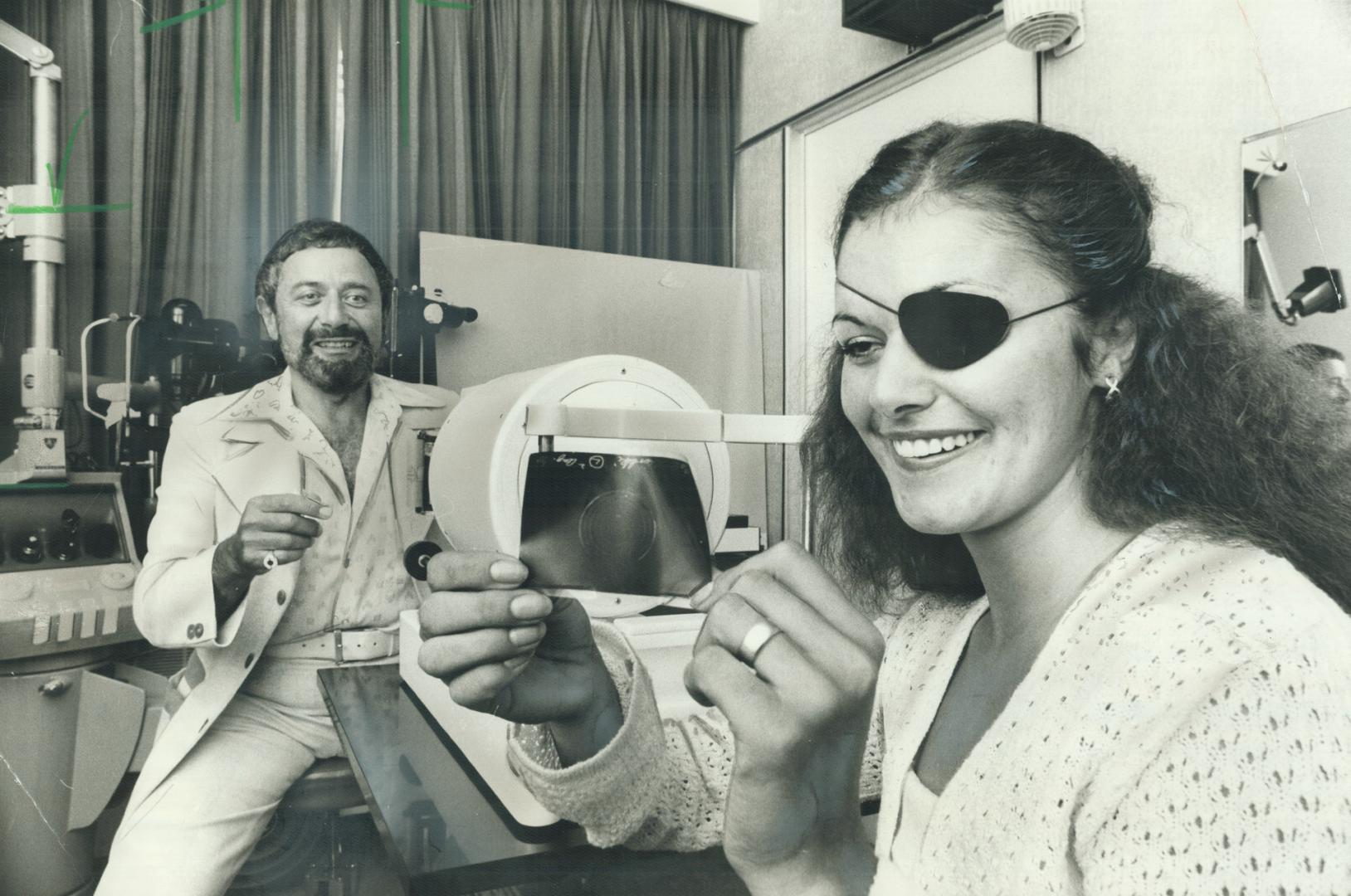 Optometrist New Paige, with some help from Debbie Powers, demonstrates one step in a procedure he uses to correct short0-sightedness by changing the shape of the cornea of the eye