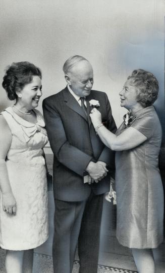 Carnation to farewell is pinned on Dr. L. M. Pidgeon, head of the department of metalurgy at the University of Toronto, by his wife at his retirement party last night. Looking on is Irene Warnock, his long-time secretary.