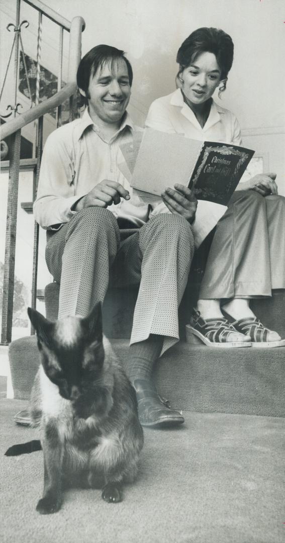 Cat-sitter James Parker of North York and his wife, Carol, go over plans for his new service while Tara, one of their own cats,fastidiously washes its face