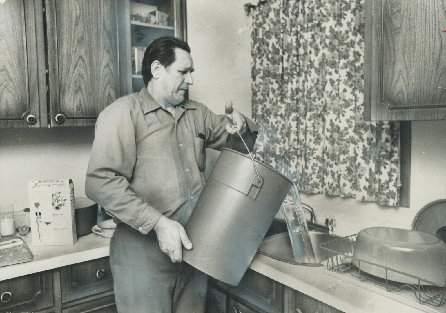 Providing running water the hard way-by running for it-John Piatka uses bucket to fill kitchen sink in his home on Macauley Ave