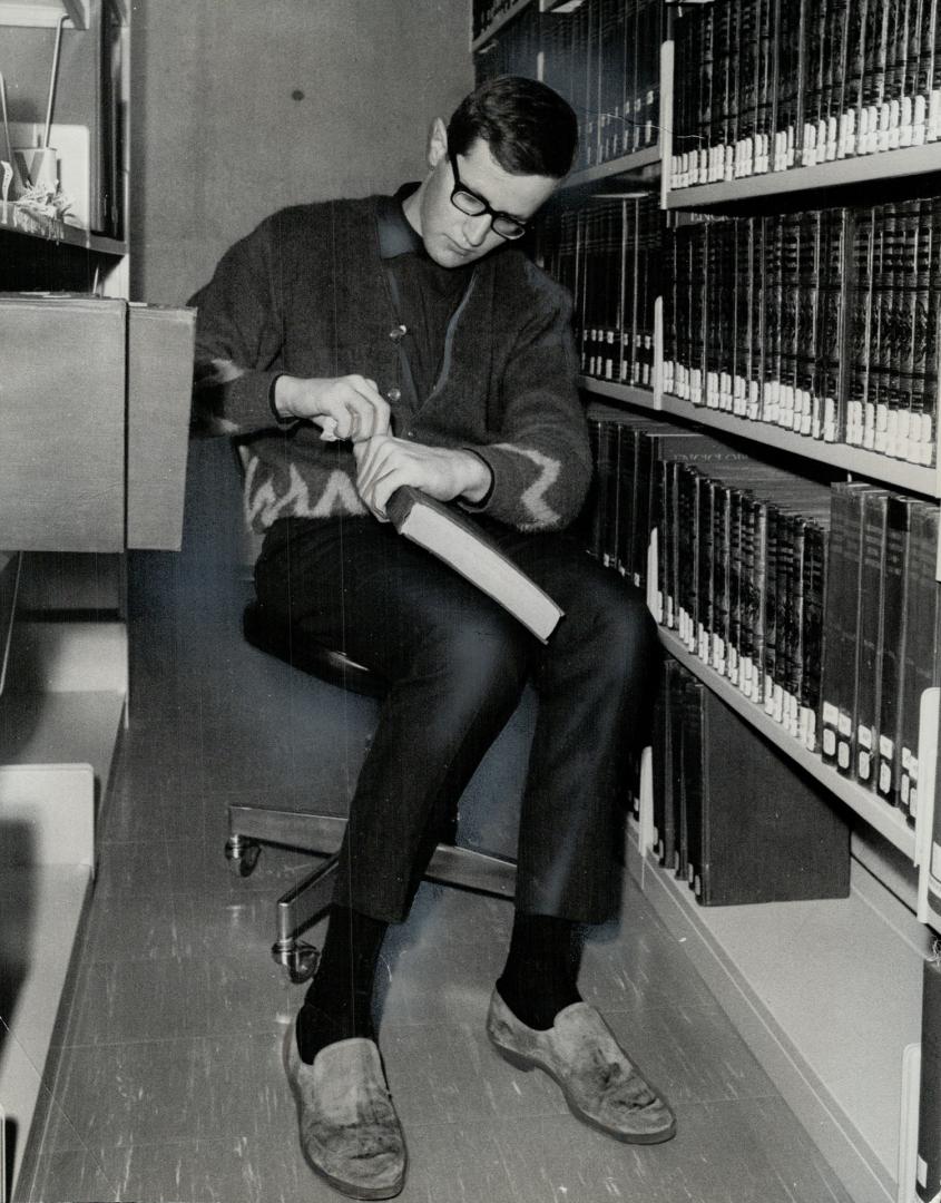 Rod Petersen works on labels in college library. He slept in snow for more than a month when his money ran out