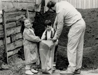 One bag full: Gardening writer Wes Porter loads up some topsoil at a local garden centre, with some help from Natalie Tate, 5, and Sam Crawford, 4.