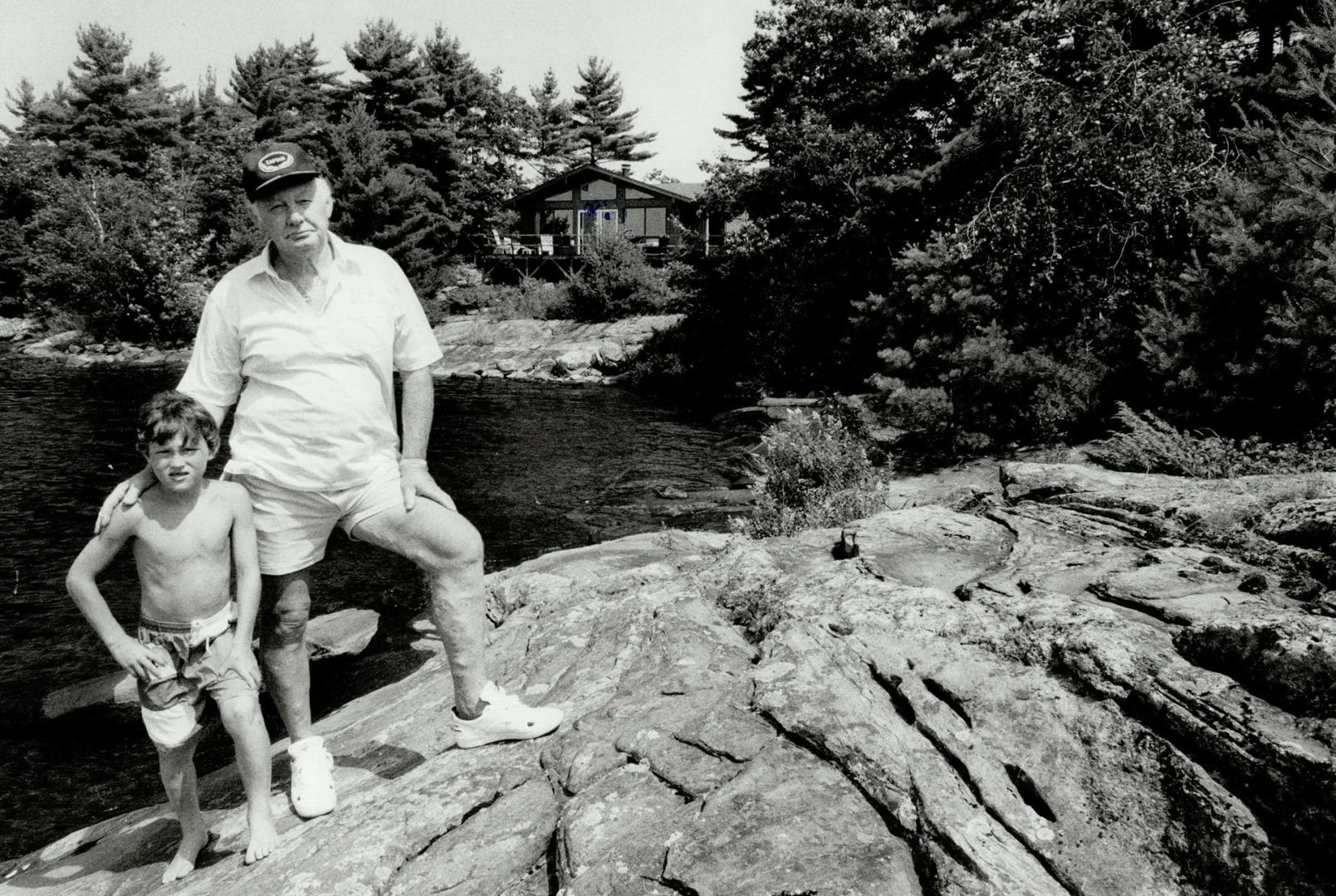 Almost idyllic: Gene Rideout of Toronto stands with grandson, Eric Newman, 8, at his cottage in Honey Harbour.