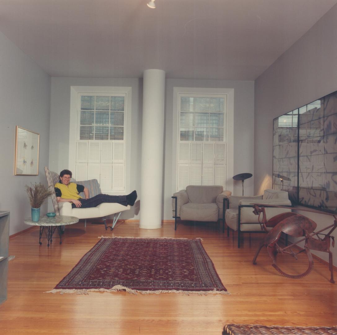 Donald Schmitt's light-filled living room includes large square windows split by a circular column he designed to enclose heat ducts.