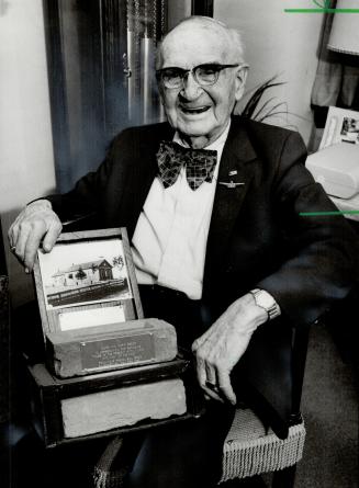 Remembers when: Clark Secor, 93, a 1904 grad of Number 6 School, holds a brick from the old building