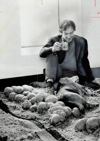 Former AD Man Ray Senior relaxes with a canine friend on one of his woven wallhangings. Pieces of material are stuffed to look like rock.