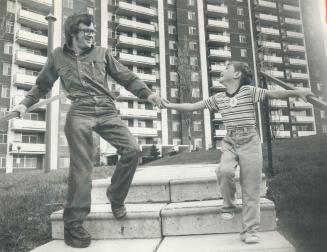 It was home: Calvin Struthers and his 6-year-old son Shawn in front of the building he was hired to take care of, despite a disability caused by polio when he was a baby