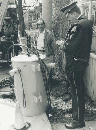 Pole position: George Traini, who chained himself to hydro property to block a new transformer, watches yesterday as Constable Rick McIntosh takes notes