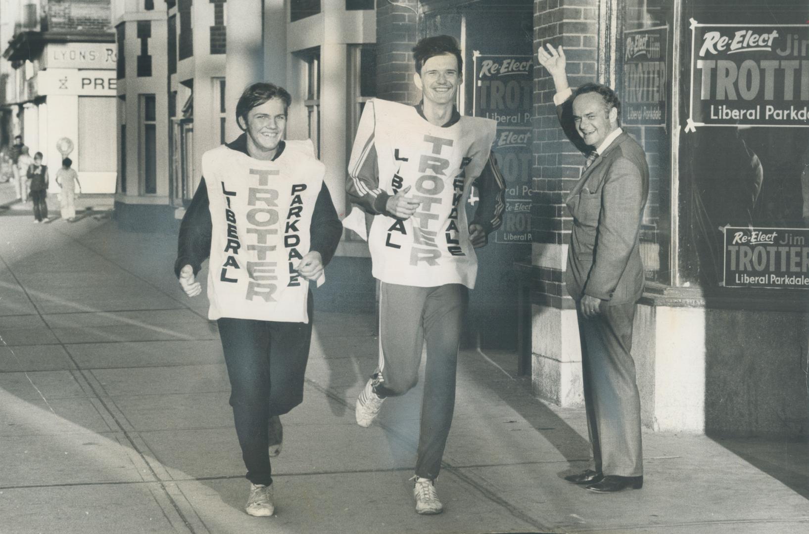 Are they Jogging or Trottering? Lest anyone think they are merely getting in a little healthy jogging, 16-year-old Harold Merten (left) and 18-year-old Chris Kuczynski wear placards to hammer home the message that they are really Trotting for Trotter, Parkdale riding's Liberal candidate, who waves encouragement to them as they pass his campaign headquarters