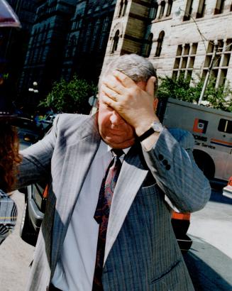 Former Executive: Constantine Tanasescu shields his face as he tries to elude a cameraman after his court appearance this morning.