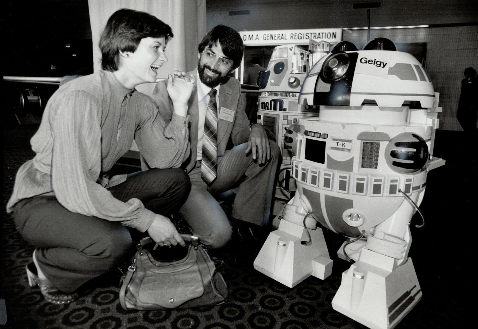 You don't say!: Dr. Paul Turner and his wife, Annice, from Perth, Ont. stopped to chat with two talking robots when they registered for the annual OMA meeting yesterday at the Harbour Castle Hilton hotel. Geigy is not from Star Wars, but he is one of the latest technicological advances.