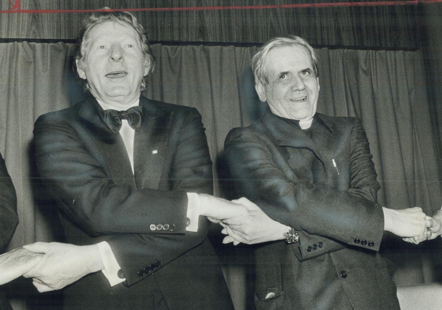 Joining hands, comedian Danny Kaye and Paul-Emile Cardinal Leger sing Auld Lang Syne at Variety Clubs International dinner at the Royal York Hotel last night