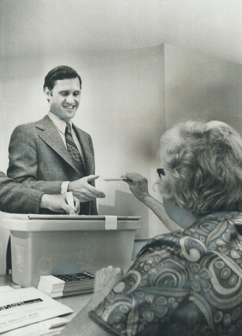 Stephen Lewis, leader of the Ontario New Democratic Party, casts his vote at a polling station on Parkcrest Dr. in his riding of Scarborough West as the deputy returning officer, Mrs. Jean Aitken, watches him. NDP now has 21 seats.