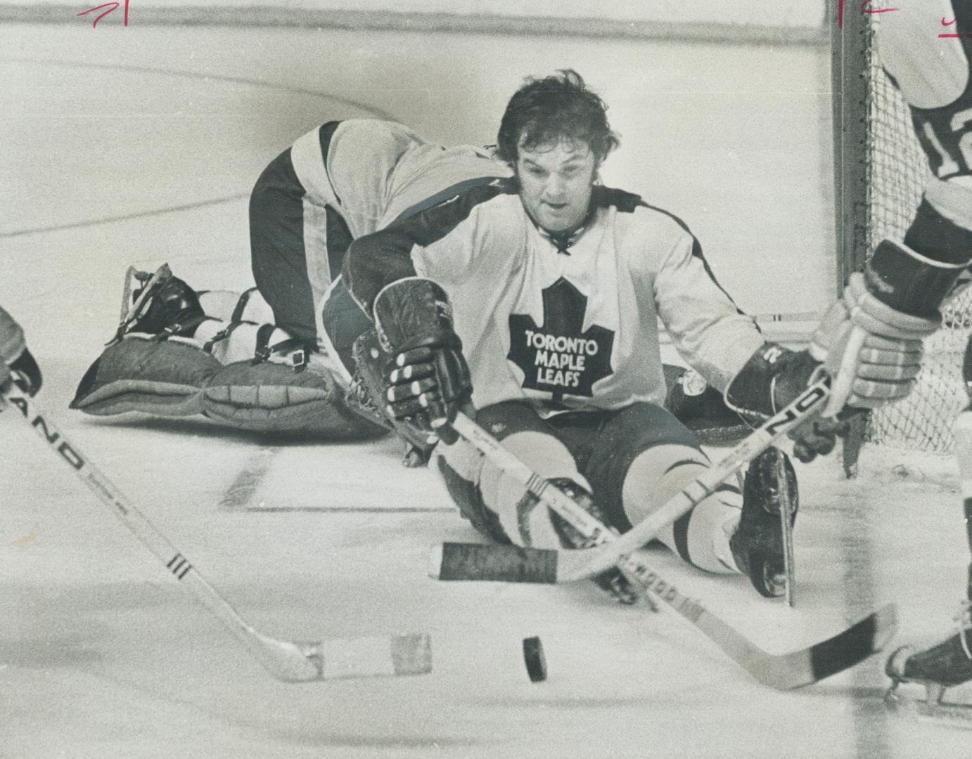 Sitting down on the job: Maple Leaf defenceman Rick Ley watches puck as two sticks attempt to whack it into Toronto net Saturday night at Gardens