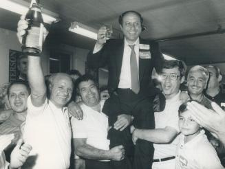 Toasting a winner: A jubilant Tony Lupusella balances a glass of champagne as cheering supporters hoist him to their shoulders after he won the new riding of Dovercourt