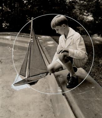 Prince Charles, 13, plays with a sailboat in a pool at his new home