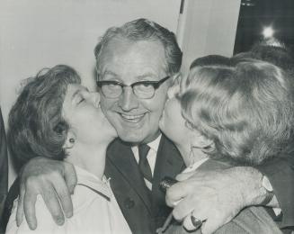 NDP leader Donald MacDonald gets double-barrelled kiss last night from his daughter Joy (right) and his wife at election headquarters in York South