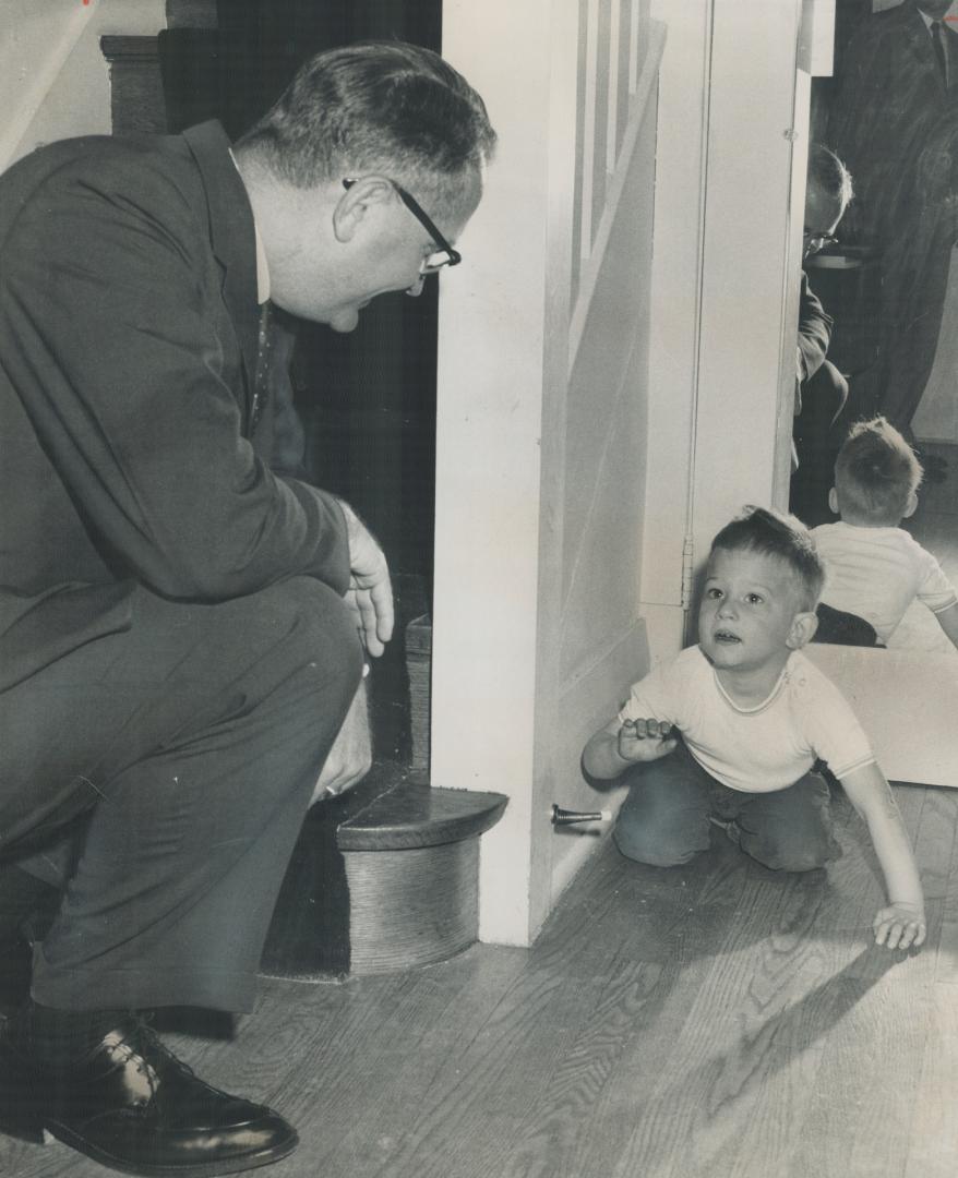 Dolls. At right NDP Leader Donald MacDonald chats with Jamie Whitewood as the three-year-old peeks around corner to watch voters at polling booth in his Wychwood Park home.