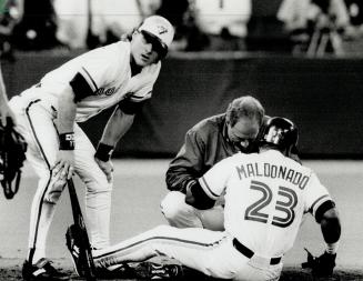 On hand: Candy Maldonado got some medical attention from trainer Tommy Craig and Kelly Gruber after getting plunked on the left hand in the eighth inning