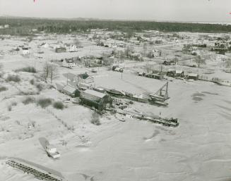 Aerial photo shows community of 500 without land link to outside. Lack of a road has caused cold war between Killarney's men and women.