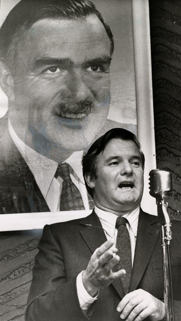 William Davis, education minister, shown speaking at Metro Conservative rally, is likely aspirant for job of Premier John Robarts, seen in portrait behind him