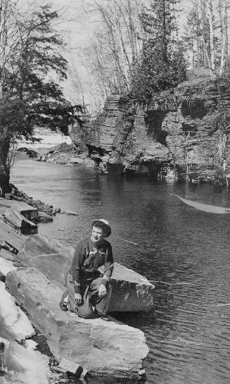 Woman kneels next to Buttermilk Falls, Ont.