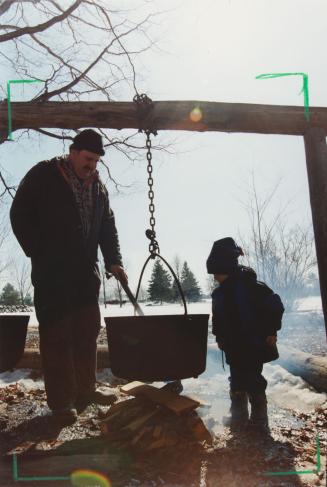 Grant Moravek mixing maple syrup as Daniel Bowers, 4, watches. Bruce's Mill Conservation Area, Ontario